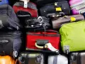 A large pile of various suitcases and bags in different colors, stacked high.