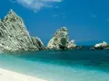White pebble beach with turquoise water and dramatic white rock formations under a clear blue sky.